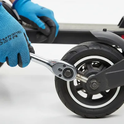 Technician carefully removing a flat electric scooter wheel from its frame with tools.